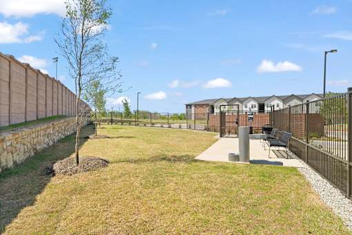 Outdoor recreation area featuring fenced green space, seating, and amenities designed for dogs and their owners.