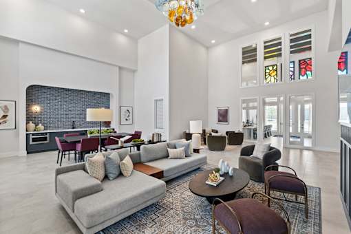 Apartment community lounge at The Esther with lounge seating, tables and kitchenette area.