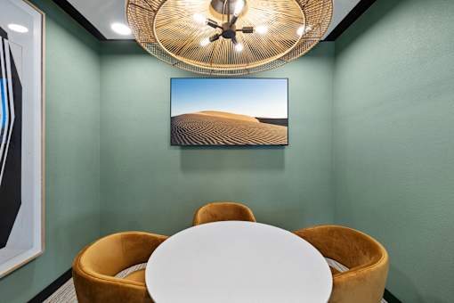 A room with a white table and a painting of a desert landscape on the wall.