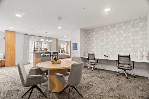 Resident business center featuring dedicated coworking workstations, collaborative meeting space, contemporary furnishings, and productivity-focused apartment community amenities.