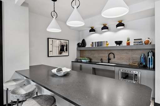 A modern kitchen with a grey countertop and a framed mirror on the wall.