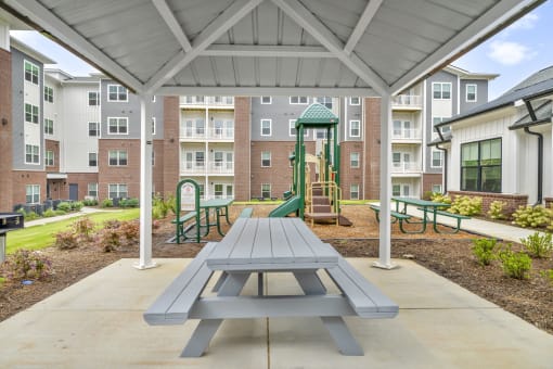 an outdoor play area with a picnic table and playground equipment at an apartment complex
