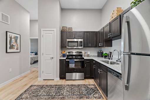 Modern apartment kitchen featuring stainless steel appliances, granite-style countertops, and ample cabinet storage.