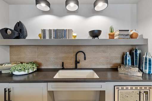 A modern kitchen with a sink, shelf, and decorative items.