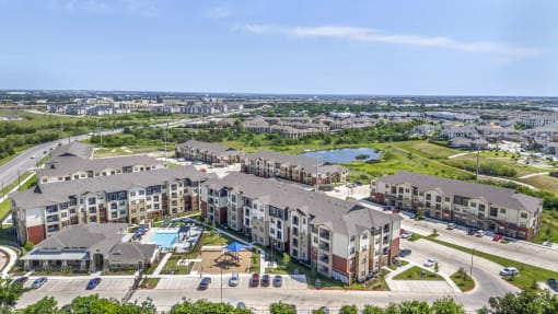 an aerial view of an apartment complex with a pool and parking lot