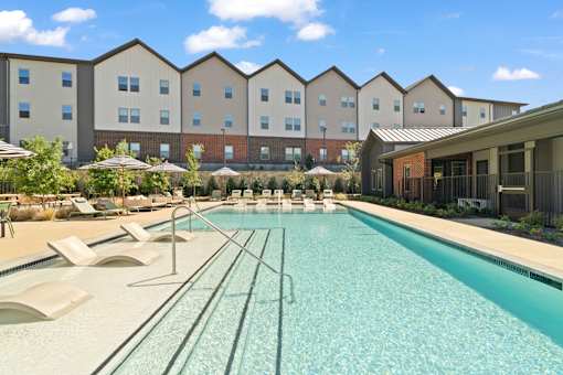 Resort-style swimming pool featuring in-water lounge seating, sun deck areas, and outdoor gathering space for residents.