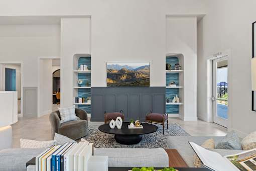 Apartment community lounge at The Esther with lounge seating, coffee table and wall-mounted TV.