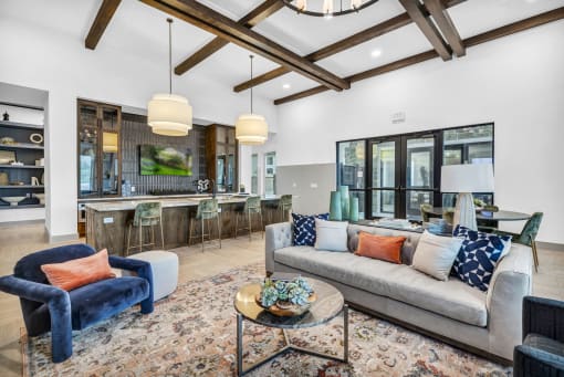 A living room with a blue velvet armchair and a grey sofa with throw pillows.