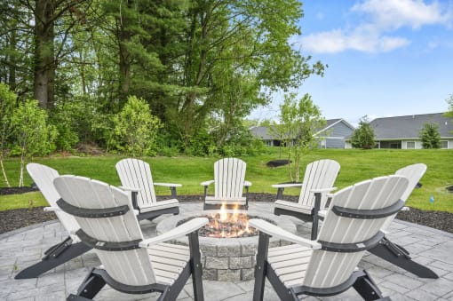 a group of white chairs around a fire pit on a patio