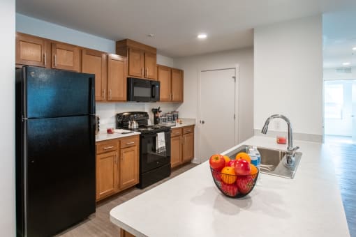 a kitchen with black appliances and a bowl of fruit on the counter