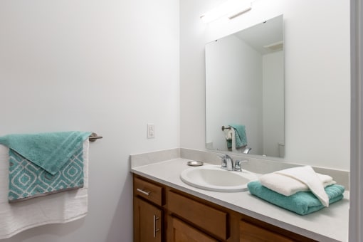 a bathroom with a sink and mirror and towels on the counter