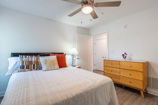 a bedroom with a bed and a dresser and a ceiling fan