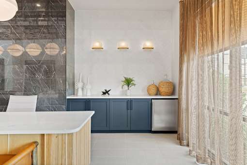 Resident lounge station featuring custom cabinetry, quartz countertops, and decorative tile accents..