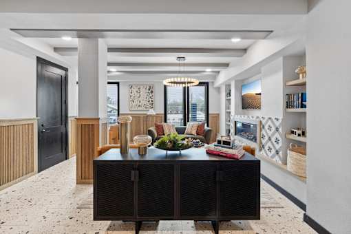 A black and white kitchen with a black fridge and a black table with a bowl of fruit on it.
