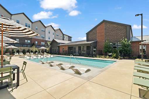 Resort-style swimming pool featuring in-water lounge seating, sun deck areas, and outdoor gathering space for residents.