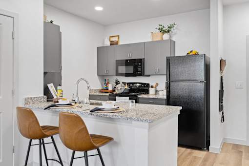 a kitchen with black appliances and a counter with bar stools