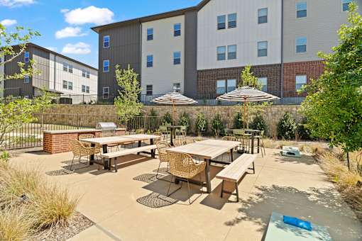 "Outdoor grilling pavilion featuring communal dining tables, shaded seating, and social gathering space for residents.