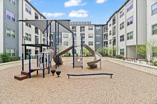 Apartment community playground featuring family-friendly recreation amenities, landscaped courtyard surroundings, and contemporary multifamily residential architecture.