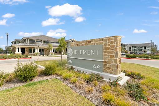 A stone sign with the word ELEMENT on it in front of a building.