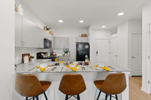 a kitchen with a counter top and a bar with four chairs