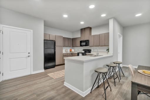 a kitchen with a bar and stools in front of a kitchen counter