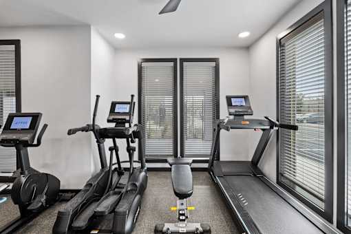 A gym with treadmills, elliptical machines, and a stationary bike.