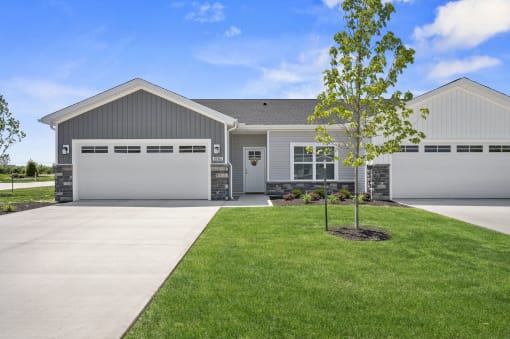 a white and gray house with a garage door and a lawn