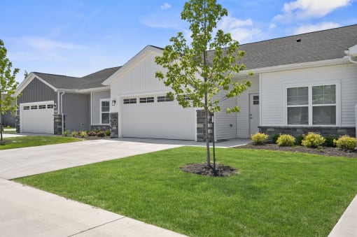 a white house with a tree in front of a driveway