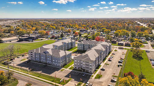 Aerial view of the apartment community featuring modern residential buildings, parking areas, and landscaped surroundings within a neighborhood setting.