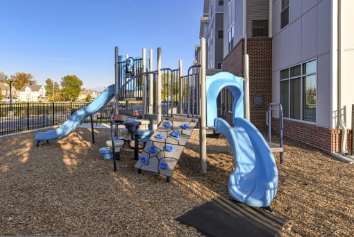a playground with two slides in front of apartment building