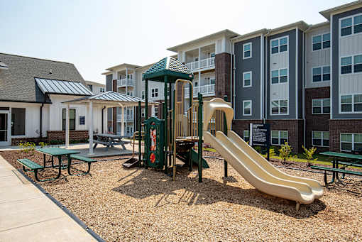 A playground with a slide and a green canopy.