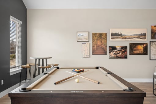 a pool table in a living room with pictures on the wall