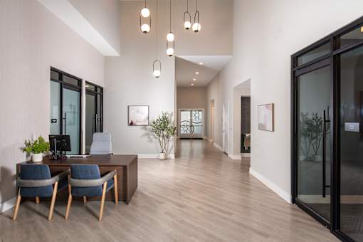 Modern office and lobby area with high ceilings, contemporary lighting, and a welcoming workspace, complemented by glass-front offices and an open layout.