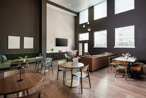 Stylish resident lounge with high ceilings, large windows, and a mix of seating areas including tables and sofas, designed for socializing and relaxation.