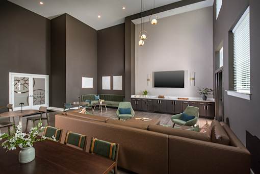 Stylish resident lounge with high ceilings, large windows, and a mix of seating areas including tables and sofas, designed for socializing and relaxation.