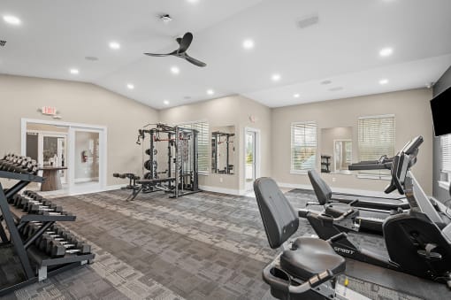 a gym with weights and cardio machines and a ceiling fan