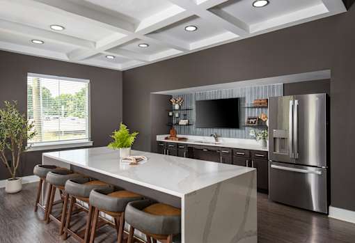 Bright community kitchen featuring an oversized island, bar seating, and sleek appliances, perfect for cooking, dining, or socializing.