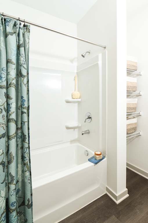 Clean tub and shower combination with built-in shelving and a sleek showerhead, offering a simple and functional bathing space.
