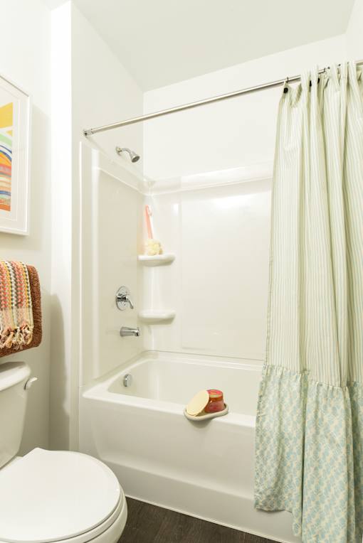 Clean tub and shower combination with built-in shelving and a sleek showerhead, offering a simple and functional bathing space.