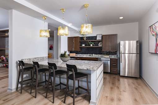 Modern kitchen with a large island, granite-style countertops, bar seating, and stainless steel appliances in an open-concept layout.