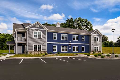 A blue and grey building with a parking lot in front.