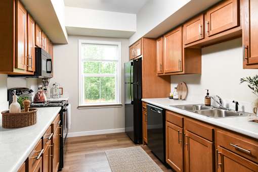 A kitchen with wooden cabinets and a black refrigerator.