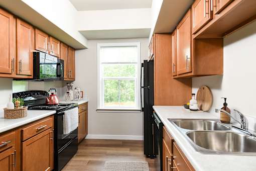 A kitchen with black appliances and wooden cabinets.