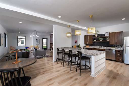 Modern kitchen with a large island, granite-style countertops, bar seating, and stainless steel appliances in an open-concept layout.