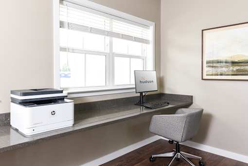 A white HP printer sits on a desk next to a window.