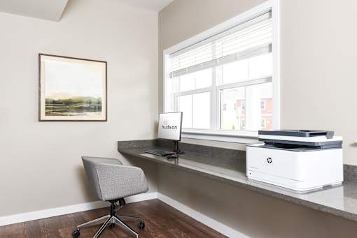 A room with a desk, chair, and a printer.