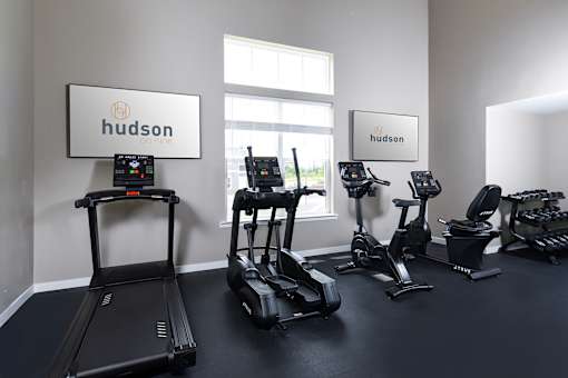 A row of treadmills and stationary bikes are lined up in a gym.