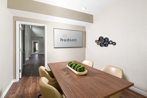 A dining room with a wooden table and chairs and a framed sign that says "hudson".