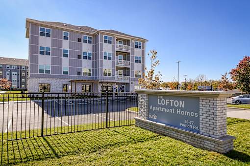 A sign for the Lofton Apartment Homes is in front of a building.