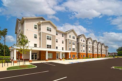 Exterior view of The Davis II in Cleveland, featuring a multi-story apartment building with brick accents, light-colored siding, covered entrances, and landscaped grounds.